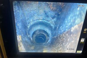 view of a dark pipe showing internal texture and depth at a six meter mark with signs of corrosion and mineral deposits